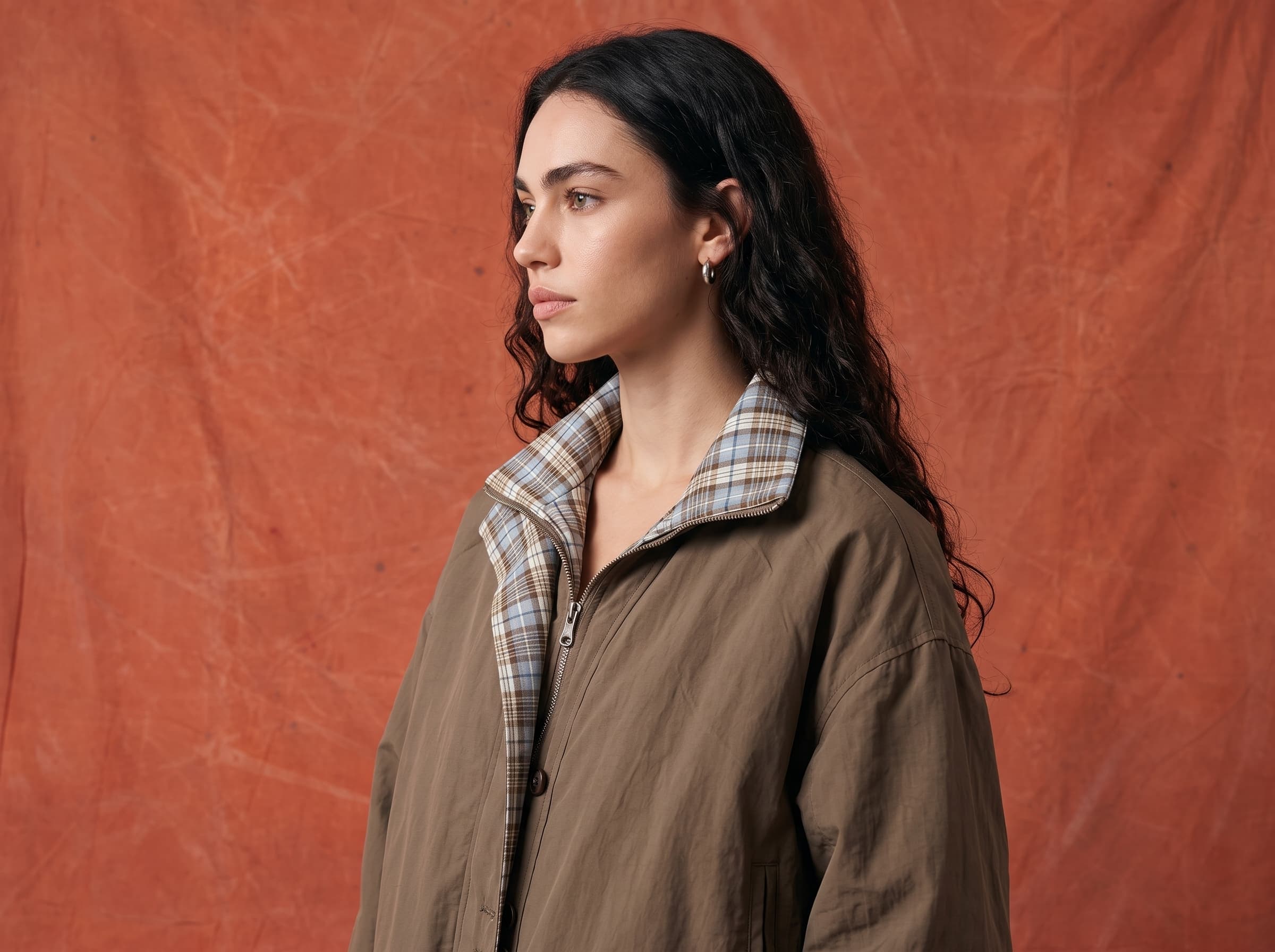 A structured khaki utility jacket with a checked shirt collar, in profile.